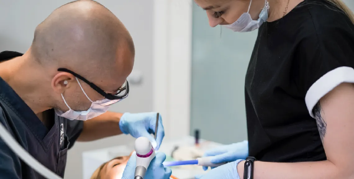 un desntista y una higienesta durante un tratamiento dental a un paciente